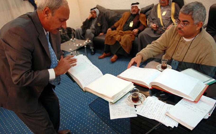 Salah Alrakabi, left, flips through the pages of several notebooks that are filled with signatures of Arabs preparing to leave Kirkuk as part of the normalization process. He coordinates a group of Shiite Arab leaders who say there have no incentive to stay in Kirkuk.