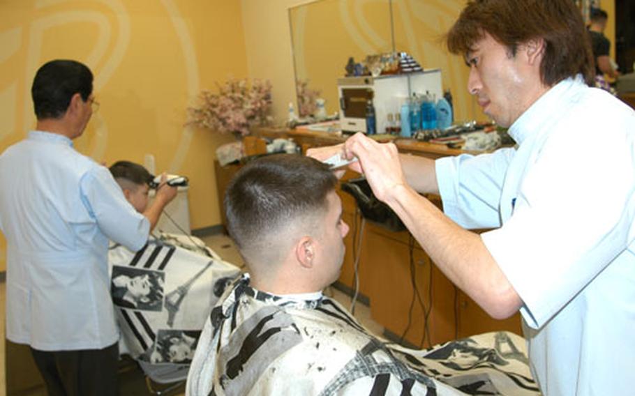 Staff Sgt. Keith Farmer, foreground, gets a haircut Monday at the AAFES main base barbershop at Misawa Air Base, Japan. Starting April 1, the Army and Air Force Exchange Service is reducing automatic discounts for haircuts and dry cleaning services in mainland Japan and Okinawa by $1.