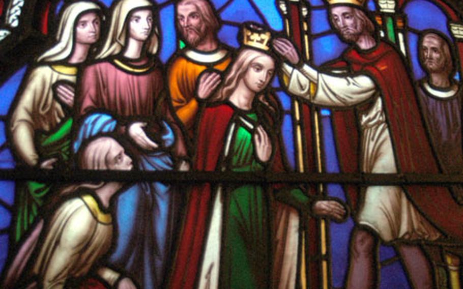 A stained glass scene of the crowning of Esther is displayed inside the Ely Cathedral.