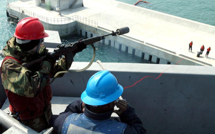 Petty Officer 2nd Class Joshua McNett uses a modified M-14 rifle with a throwing attachment to fire a guideline to moorings at the port in Busan, South Korea.