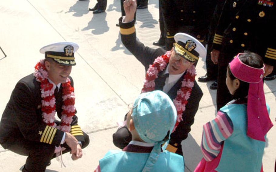 USS Ronald Reagan commanding officer Capt. Terry Kraft, left, and commander of Carrier Strike Group 7 Rear Adm. Charles Martoglio accept leis Thursday from children after mooring in Busan, South Korea.