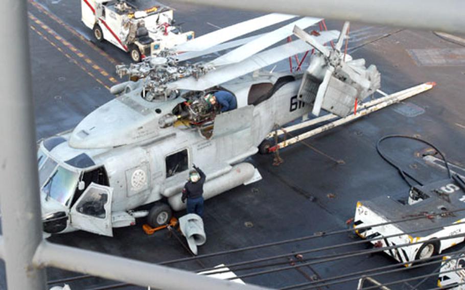 Sailors perform maintenance on an SH-60 Seahawk helicopter Thursday aboard the USS Ronald Reagan.