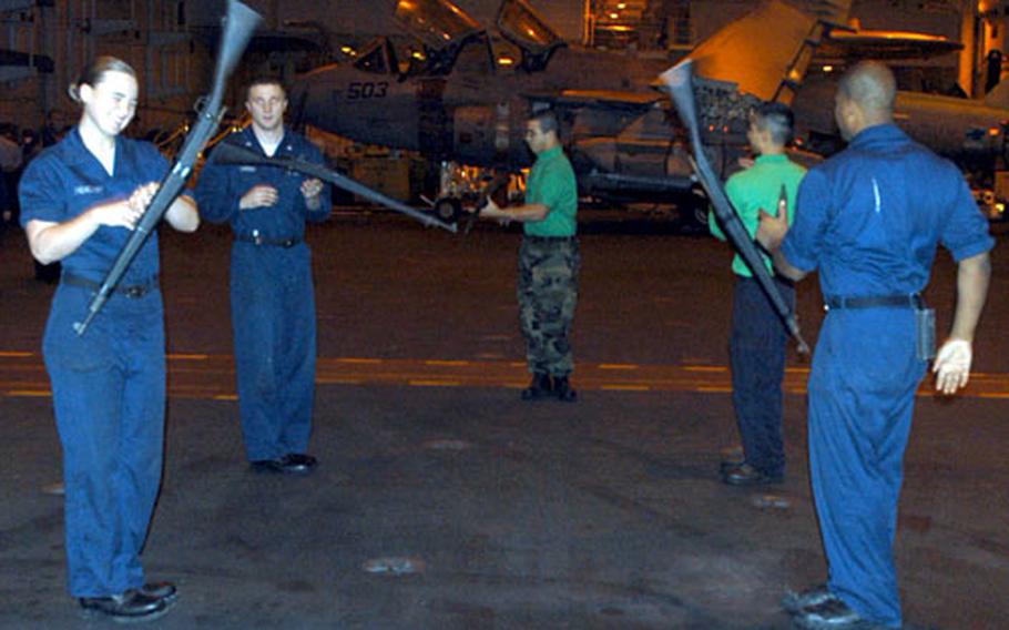 Members of the USS Ronald Reagan Honor Guard practice rifle drills late Wednesday night as their ship makes its way toward Busan, South Korea.