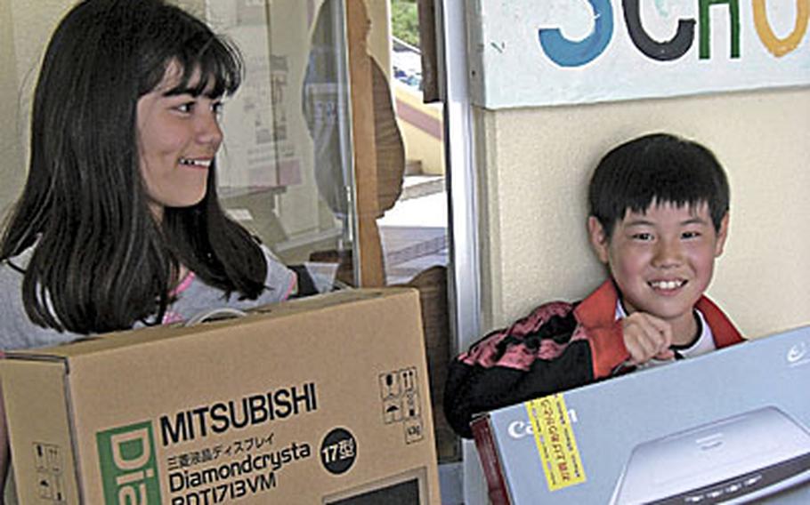 Sakura Sunagawa, left, and Naoyuku Komatsu, both third-graders at Okinawa AmerAsian School, show off new computer equipment donated to the school on Wednesday by American Legion Post 28 and Sunny-Net.