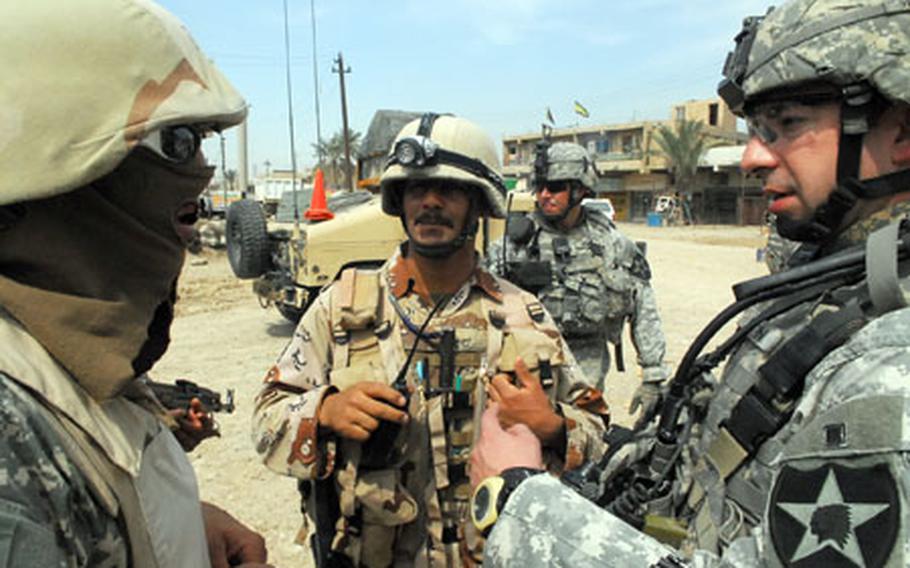 1st Lt. Jonathan Martin, right, speaks to an Iraqi Army soldier through an interpreter, left, during a joint Baghdad security plan patrol recently. The interpreter, an Iraqi, has covered his face because he is worried that he or his family will be targeted for assassination if he is recognized by insurgents.