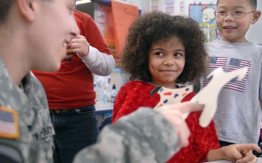 Spc. Miranda Demoines, a soldier from the 1st Cavalry Division, tests out her crafts skills with Emily Langston as Ryan Brumback looks on Thursday at Ramstein Elementary School. Demoines, along with eight other wounded soldiers receiving outpatient care at Landstuhl Regional Medical Center, spent time with the second graders.