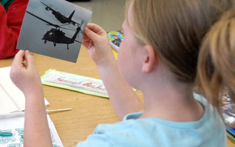 Hannah Barker, 8, a third-grader at E.C. Killin Elementary School, looks at a photo of a plane refueling a helicopter. The photos were passed around Friday by airmen with 17th Special Operations Squadron who corresponded with the kids during deployment.