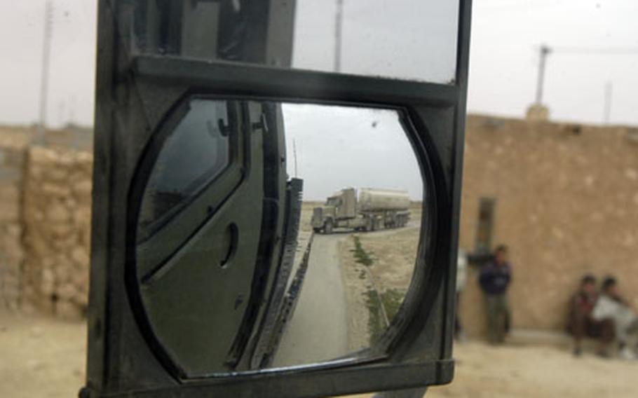 A KBR truck pulling a fuel tank is seen in the review mirror of a seven-ton U.S. Marine Corps truck, which stopped in a small town Saturday near camp al Qa’im to provide security for a 41-truck convoy mission.