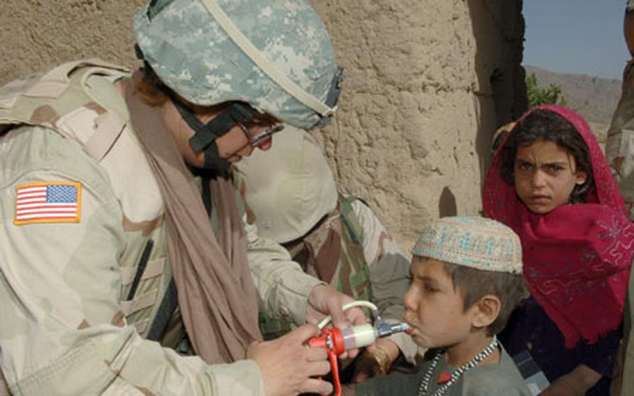Petty Officer 1st Class Michele Reed, assigned to the 405th Civil Affairs Battalion, gives a young Afghan boy a deworming solution to help with worms during a village medical outreach (VMO) conducted by Task Force Warrior on June 12, 2006 in Andarh village, Daychopan district, Afghanistan.