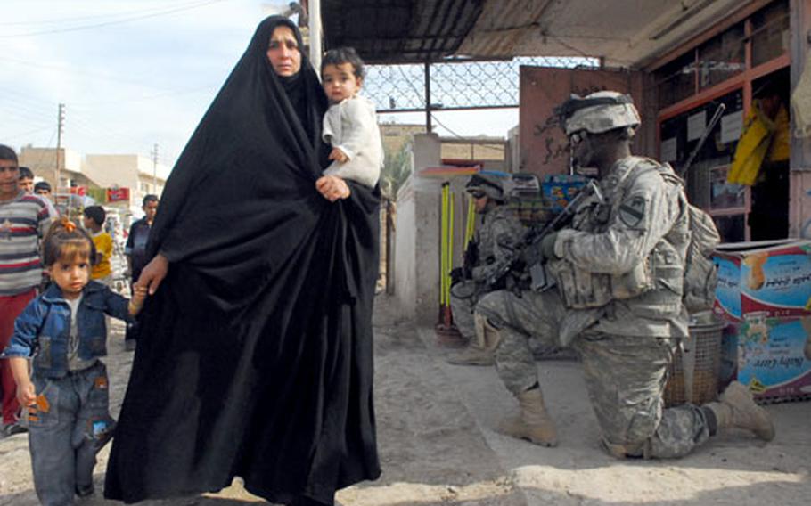 An Iraqi woman walks her children past a group of U.S. soldiers with Company C, 1st Battalion, 8th Cavalry Regiment, 1st Cavalry Division in the southeastern Baghdad neighborhood of Obaidy. The 1-8 CAV is currently attached to the 2nd Infantry Brigade Combat Team, 2nd Infantry Division.