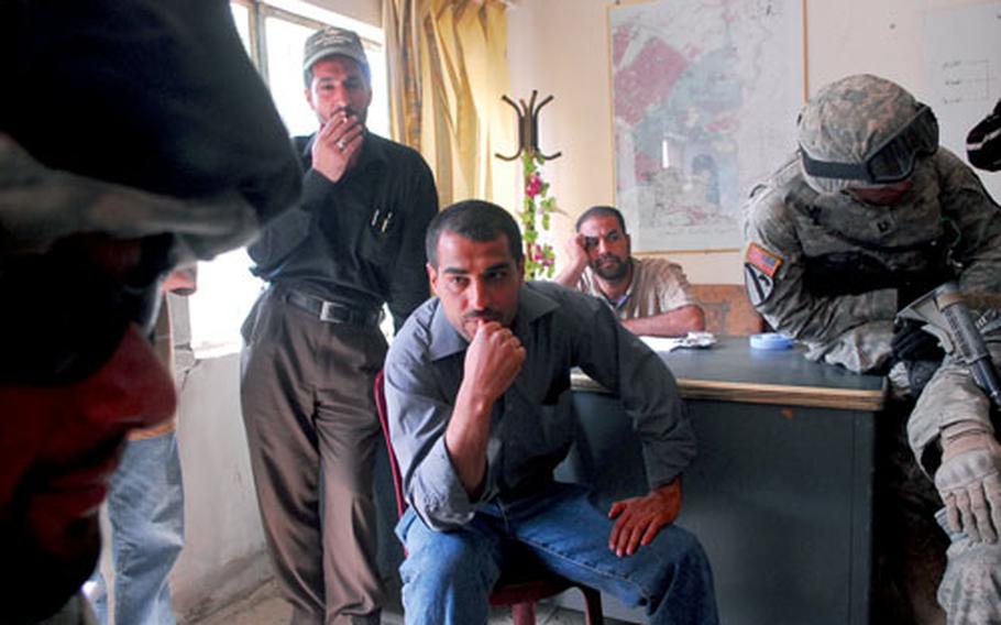 A group of local garbage collectors and suspected Mahdi Army militiamen in the east Baghdad neighborhood of Oubaidy cast wary glances at U.S. soldiers and their Iraqi interpreters during a recent visit to the group&#39;s office.