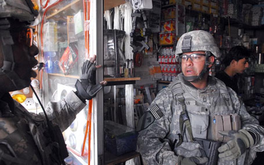 Sgt. 1st Class Muhammad Glass, 34, of Philadelphia, left, and acting First Sgt. Jose Moran, 39, of San Juan, Puerto Rico, shop for light bulbs and extension cords in eastern Baghdad on Wednesday.