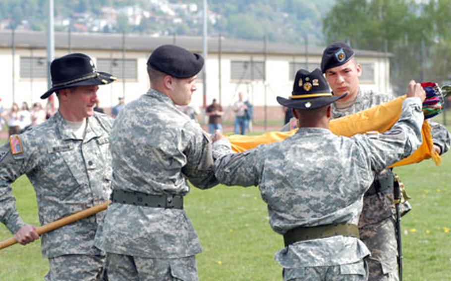 Lt. Col. Matthew McKenna, commander of the 1st Squadron, 1st Cavalry Regiment, holds the staff as Pfc. Richard Saber, center left; Master Sgt. Sheldon Griffin, acting command sergeant major (back to camera); and Pfc. Chad Espinosa roll the colors during the unit&#39;s inactivation ceremnoy Tuesday at Armstrong Barracks in Büdingen, Germany.