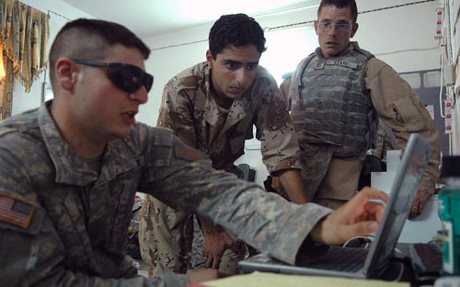 Two American soldiers talk to an Iraqi police officer, center, about plans to secure the Suwa Joint Security Station, about 10 km south of Ramadi&#39;s city line.