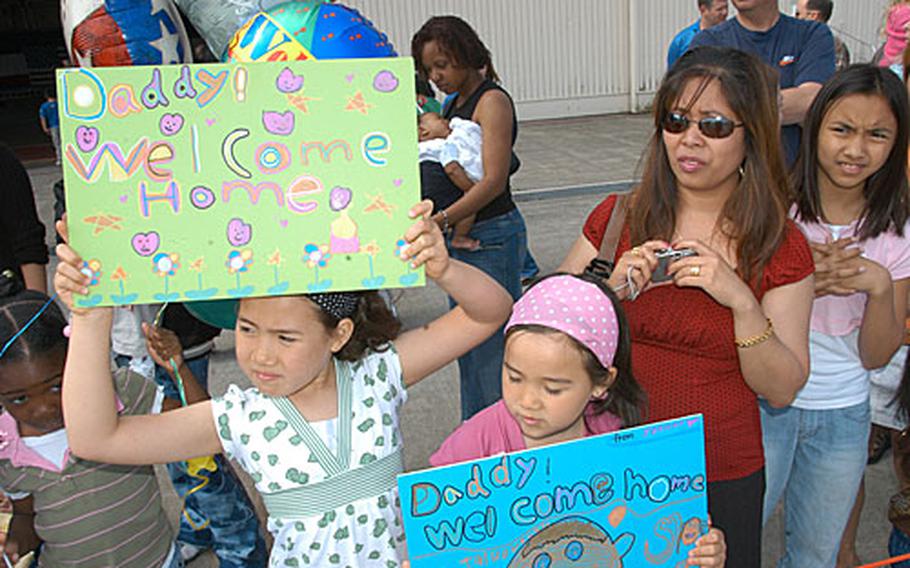 Trinity Loucks, 7, left, and Jazlynn Loucks, 5, proudly display their homemade signs welcoming their dad, Staff Sgt. Michael Loucks, home from Iraq.