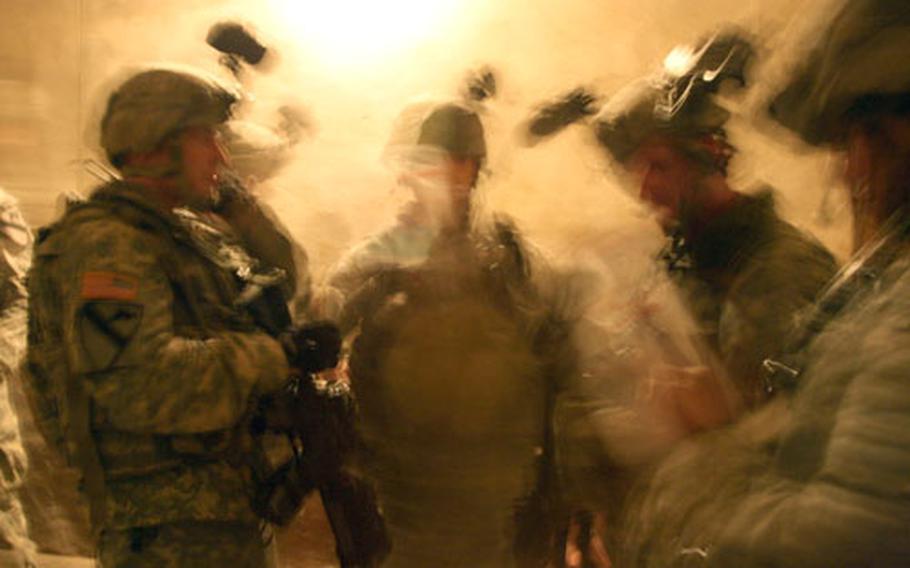 Combat leaders with the 1-12th Combined Arms Battalion confer before troops begin searching house to house during a midnight raid on the village of Nahir Shallub for weapons and information on insurgents. Information from a previous raid that freed 42 kidnapped Iraqi men being held by al Qaida in a nearby village suggested that more secret prisons could be in the area. No prisoners were found in Nahir Shallub.