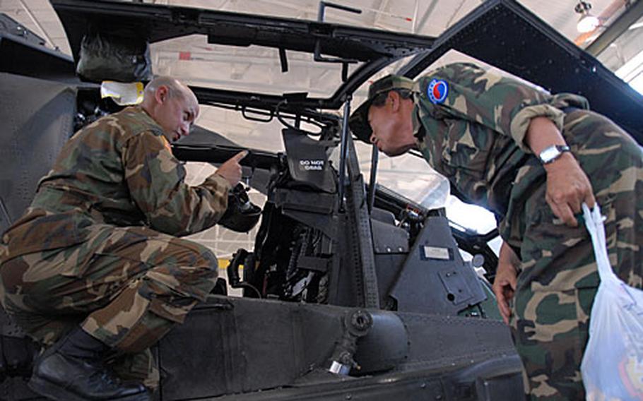 Chief Warrant Officer Greg White points out features of a helicopter at K-16 Air Base to a visiting Korean veteran, part of a group that fought against the North Koreans when they were teenagers.