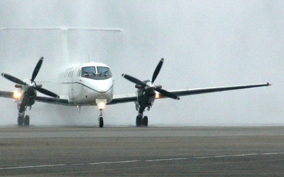 One of the three C-12 planes that are scheduled to replace the C-21s, drives through a arch of water being sprayed from firetrucks as it is welcomed to Yokota Air Base.