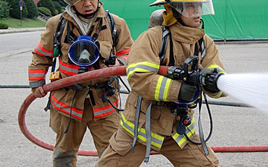 Firefighters from the Yongsan Garrison Fire Departments simulate fighting a fire during a mass casualty exercise.