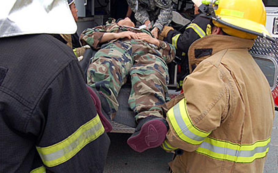 Medical personnel and firefighters from the Yongsan Garrison and Yongsan-gu fire departments load casualties onto stretchers during a mass casualty exercise.