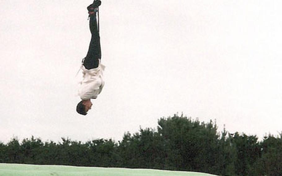 Petty Officer 1st Class Jonathan Edmiston works to escape from a straitjacket during a bungee jump in England in 1997.
