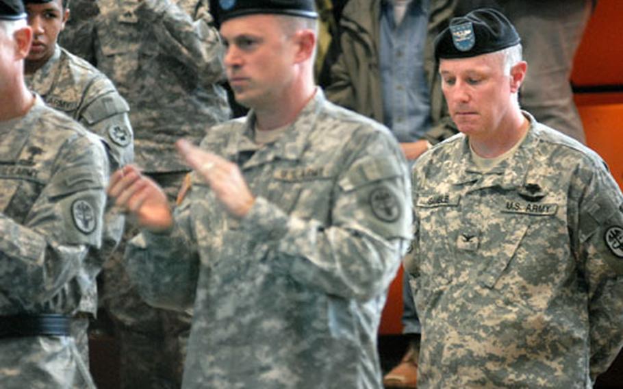 Col. Bryan Gamble, right, the outgoing commander of Landstuhl Regional Medical Center, dips his head as the crowd rises for a standing ovation Tuesday at the Landstuhl gym. Col. Brian Lein, the new LRMC commander, is at center.