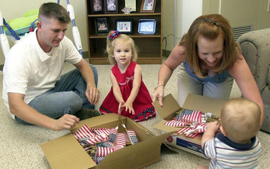 Gunnery Sgt. Eldar and Rebecca Krueger show their young children, Abigail, 3, and Oliver, 8 months, the 400 flags the family plans to distribute to homes on Camp McTureous on Wednesday.