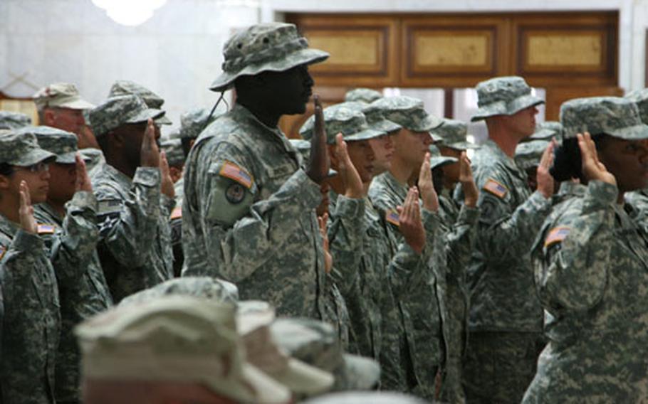 Troops raise their hands and swear the oath of allegiance to the United States, as they become naturalized citizens during a July Fourth ceremony at Camp Victory in Iraq.
