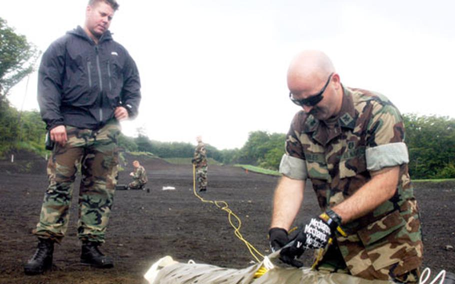 Chief Petty Officer Jason Kennedy, left, watches Petty Officer 1st Class Arick Hiles prepare 125 pounds of C-4 plastic explosive for detonation Monday at Camp Fuji, Japan. The members of Yokosuka Naval Base&#39;s explosive ordnance disposal detachment practice demolition training at Camp Fuji quarterly, they said.