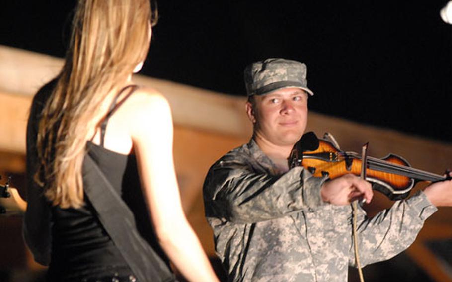 Medic and classically-trained violinist Pfc. Marcus Mullins, 22, of Nashville, Tenn., smiles at bassist Jessica Fagre, of Boulder, Colo., during a concert by country music singer Brian Stace at Kandahar Air Field in Afghanistan.