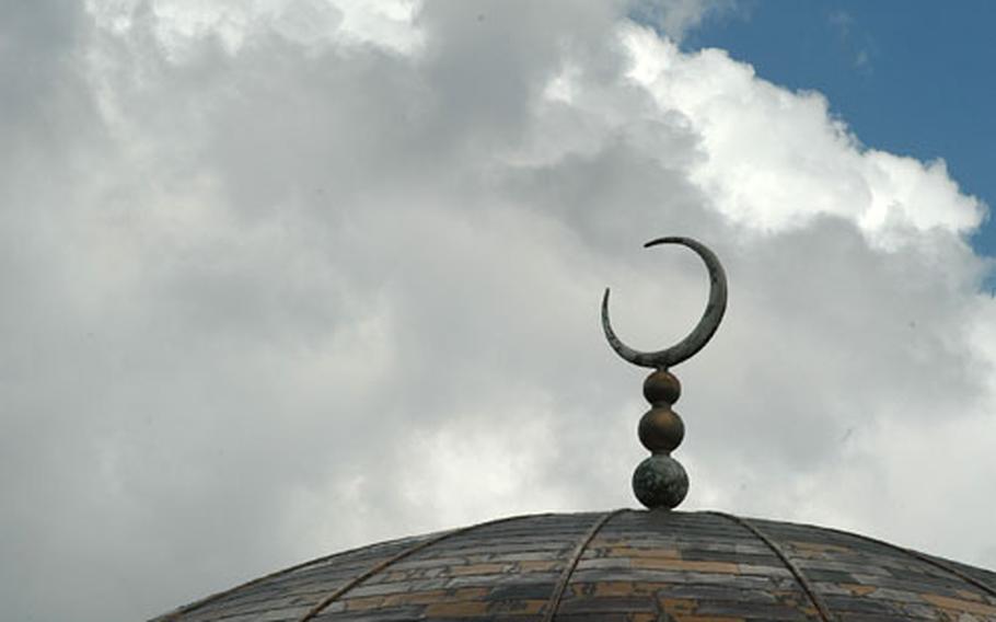 A crescent moon sits atop Regent Park Mosque&#39;s golden dome.