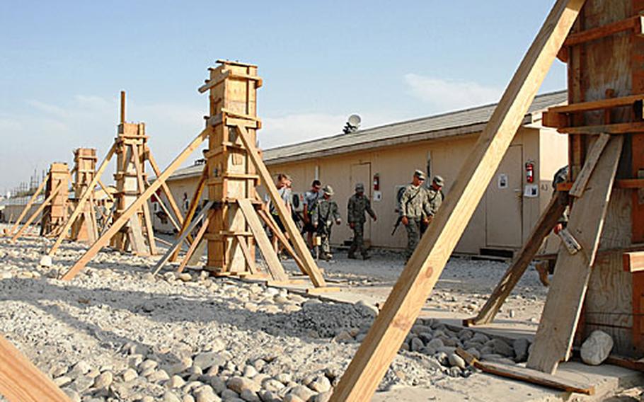 Troops stationed on Forward Operating Base Fenty, part of Jalalabad Air Field in Afghanistan, walk by the Afghan-made framework for what will be the new home of the base&#39;s medical company and forward surgical team.