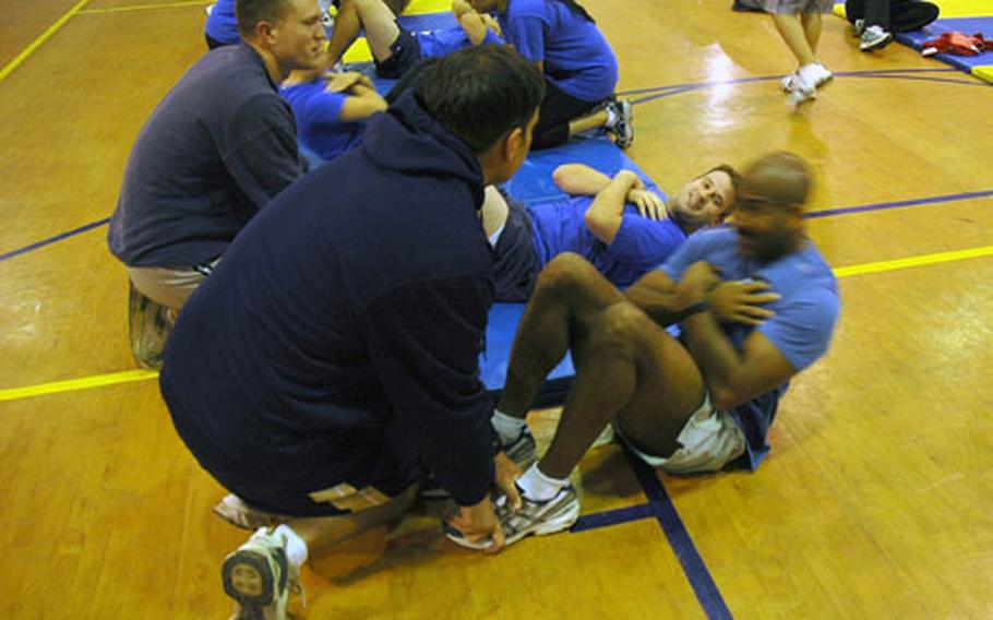 Cmdr. Reggie Howard, performs the curl-up portion of the Navy&#39;s semi-annual Physical Fitness Assessment held aboard Naval Air Station Sigonella. This summer, Navy Region Europe kicked off "Family Fitness," a new program that gets the entire family involved in physical fitness and healthy lifestyle practices.