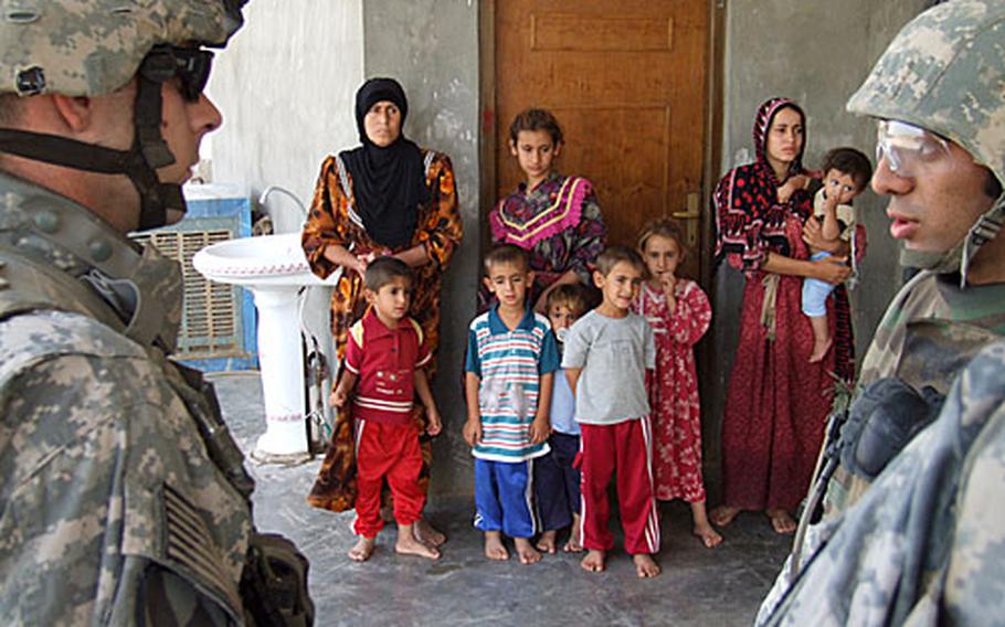Army 1st Lt. Christopher Ricciardi, 27, of Edwardsville, Ill., and an interpreter consult with an Iraqi family as they tell the women and children that a new combat outpost has been set up by the regiment directly next to their house.