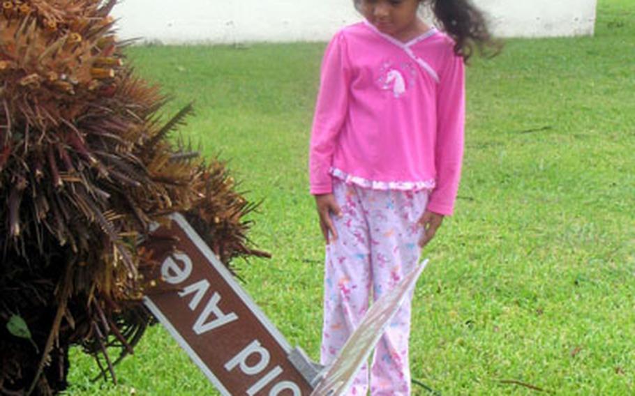 Isabella Alexandra Henao, 4, the daughter of Marine Sgt. Major Jose Henao, surveys an errant street sign swept off its pole near her home on Kadena Air Base. Typhoon Man-Yi&#39;s winds reached gusts exceeding 105 mph.