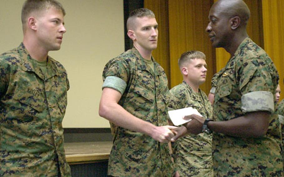 Sgt. Maj. of the Marine Corps Carlton W. Kent gives his coin to several Marines on Tuesday at Camp Foster.