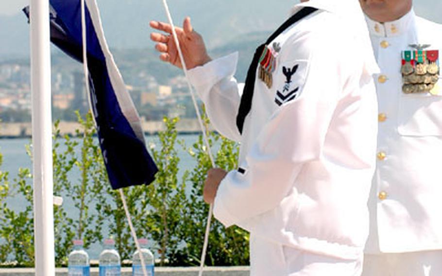 A Navy quartermaster ceremoniously "breaks" the flag of Rear Adm. Michael Groothousen during a change-of-command ceremony, unfurling the flag to signify Groothousen&#39;s assuming command of Navy Region Europe and Maritime Air Naples.