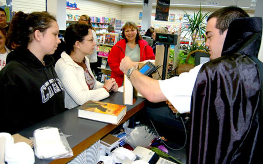 Sarah McKay, left, accompanied by her sister, Rhianne, and mother, Melinda, rose early Saturday morning and traveled from Brunssum to be the first to purchase "Harry Potter and the Deathly Hallows" at AAFES&#39; BookMark at U.S. Army Garrison Schinnen. Sales associate Jon Calderwood, who made the sale, joined other staff members in dressing up the store and themselves.