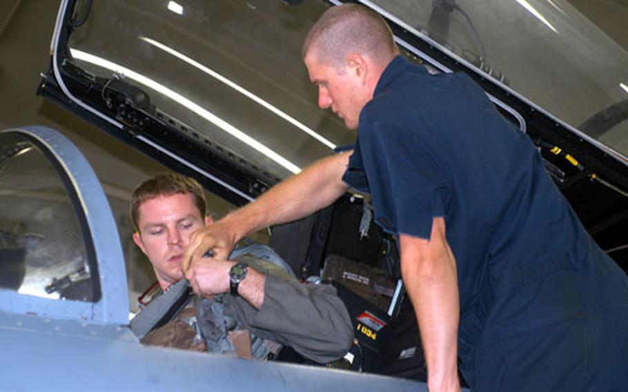 Ceccardi helps F-15 pilot Capt. Jonathan Hough strap in prior to a training sortie.
