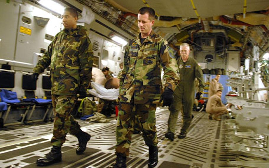 Master Sgt. Anthony James, Senior Master Sgt. John West and Col. Joe Davis transport a patient from a C-17 coming from Iraq onto Ramstein Air Base in Germany on July 5.