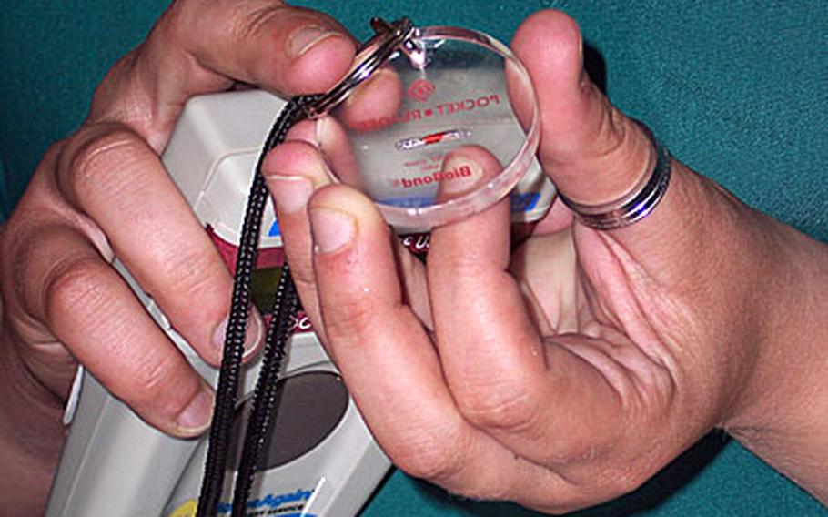 A small red microchip, shown here at the center of a clear, round disc, must be implanted in dogs, cats and some other domesticated pets belonging to status of forces agreement personnel in South Korea. A recent regulation on pet ownership also sets rules for pet registration and bans abandonment.