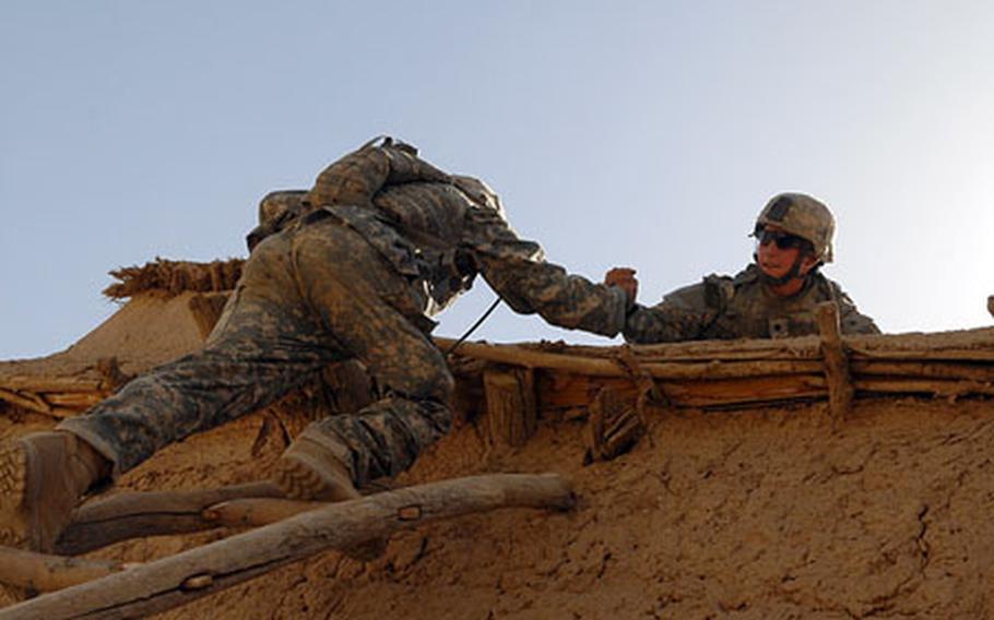 Soldiers from Company A, 1st Battalion, 508th Parachute Infantry Regiment, 82nd Airborne Division, use a rickety wooden ladder to scale the roof of a mud-walled home while providing security for a village shura recently in Zabul Province, Afghanistan.