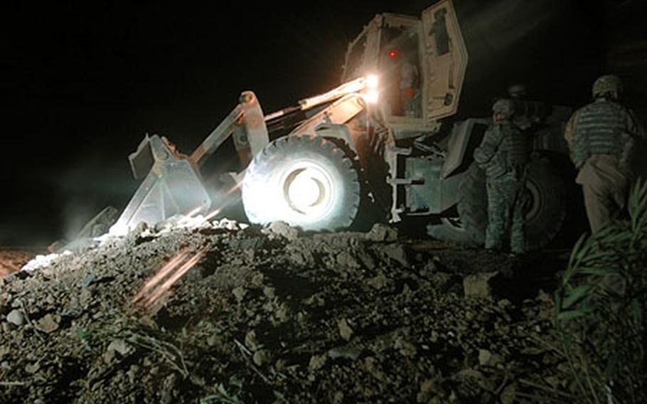 Members of the 60th Engineer Company use heavy equipment while repairing a crater left when a donkey reportedly tripped a roadside bomb.