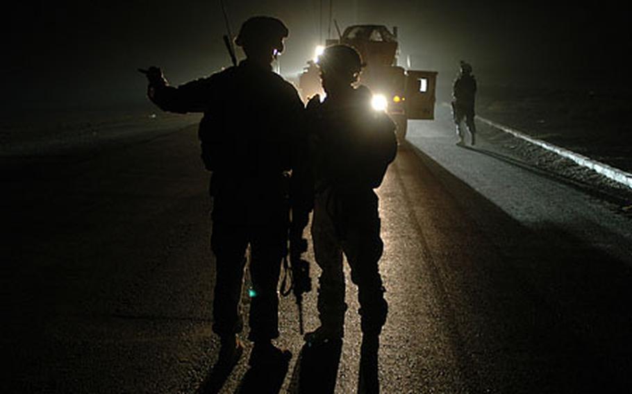 Members of an anti-roadside bomb team search an area at night near the remote northern Iraqi city of Qayyarah. The soldiers are with the 5th Battalion, 82nd Field Artillery Regiment. The battery was recently hit three times in one week by roadside bombs, but sustained no casualties.