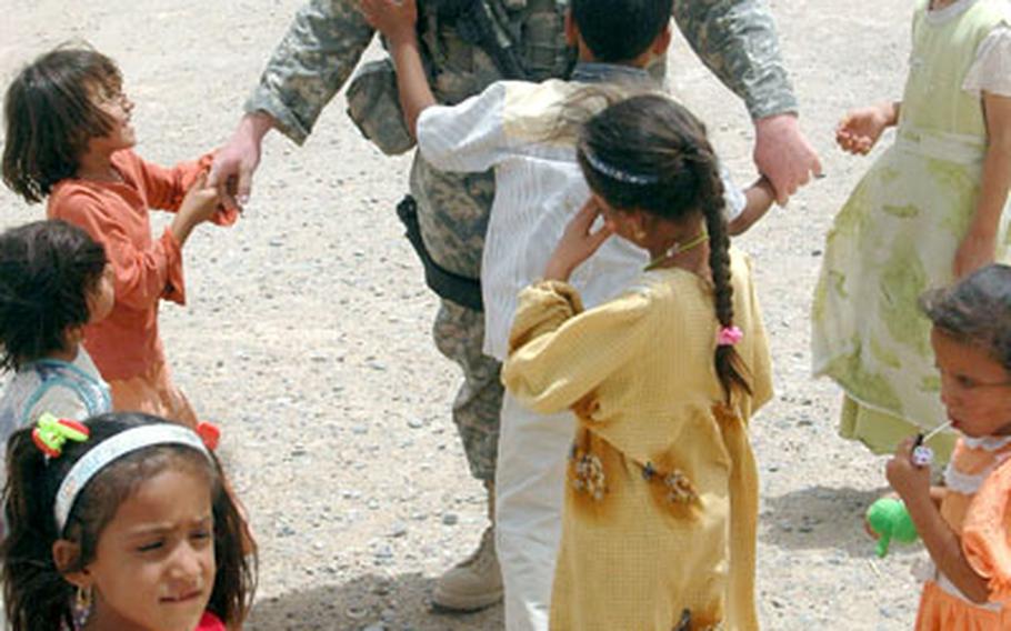 Pfc. Theron Webb, 20, of Searsy, Ark., plays with village children while supervisors in his unit check a nearby well. Webb is a reservist member of the 431st Civil Affairs Battalion, currently attached to the 5th Battalion, 82nd Field Artillery Regiment, 1st Cavalry Division.