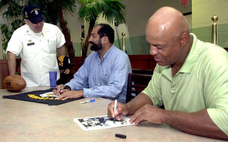 Lydell Mitchell, right, signs a photo Thursday while Pittsburgh Steelers Hall of Famer Franco Harris signs a jersey for Sgt. 1st Class Dewey Phillips.