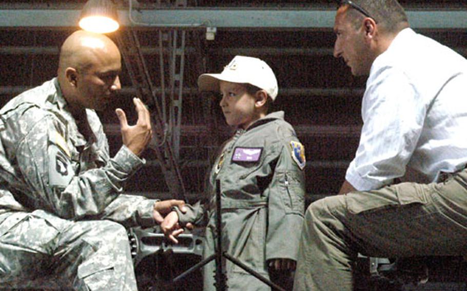 Army 2nd Lt. Jose Marquez explains a few things about the Black Hawk while sitting on top the helicopter with Daniele Montico, 6, and his father, Mauro.