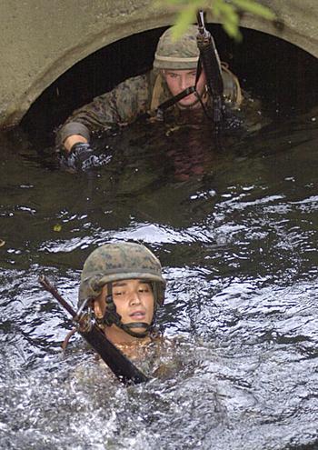 Marines with Marine Air Control Group 18 traverse a partially-submerged culvert and then use a rope to pull them across the deeper open water Friday at an obstacle on the endurance course at the Jungle Warfare Training Center on Camp Gonsalves.