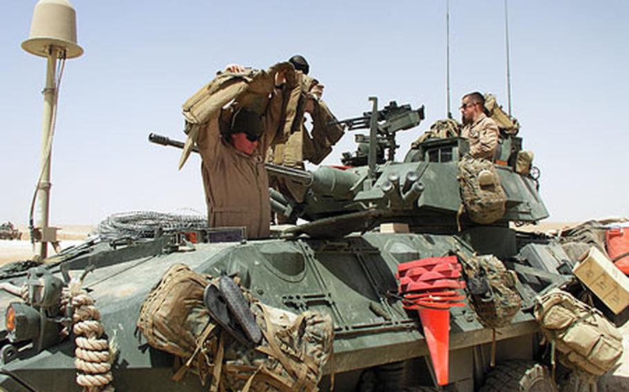 In western Anbar province, Marines of Company C, 1st Light Armored Reconnaissance Battalion, don their body armor before leaving Combat Outpost Rawah for a long-distance raid in the desert. The task force commander is seeking approval to have Marines patrolling area cities do so without helmets and with less body armor than they usually wear. Marines would keep the unused gear at the patrol base and would resume using it if needed.