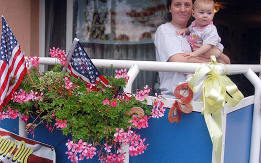 Katja Sovine holds 9-month-old Cheyenna on the decorated balcony of her apartment in Askren Manor in Schweinfurt, Germany. Sovine is the wife of Staff Sgt. Carl Sovine of Company B, 1st Battalion, 77th Armor Regiment.